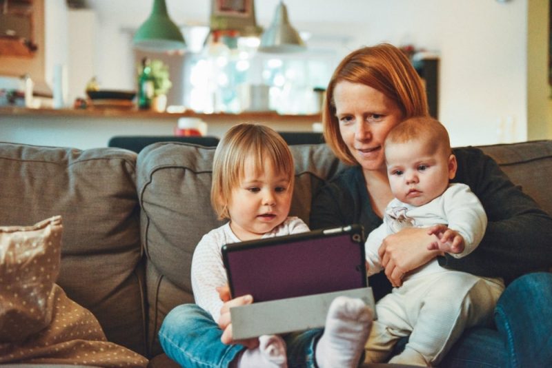 mother playing with an ipad with two children